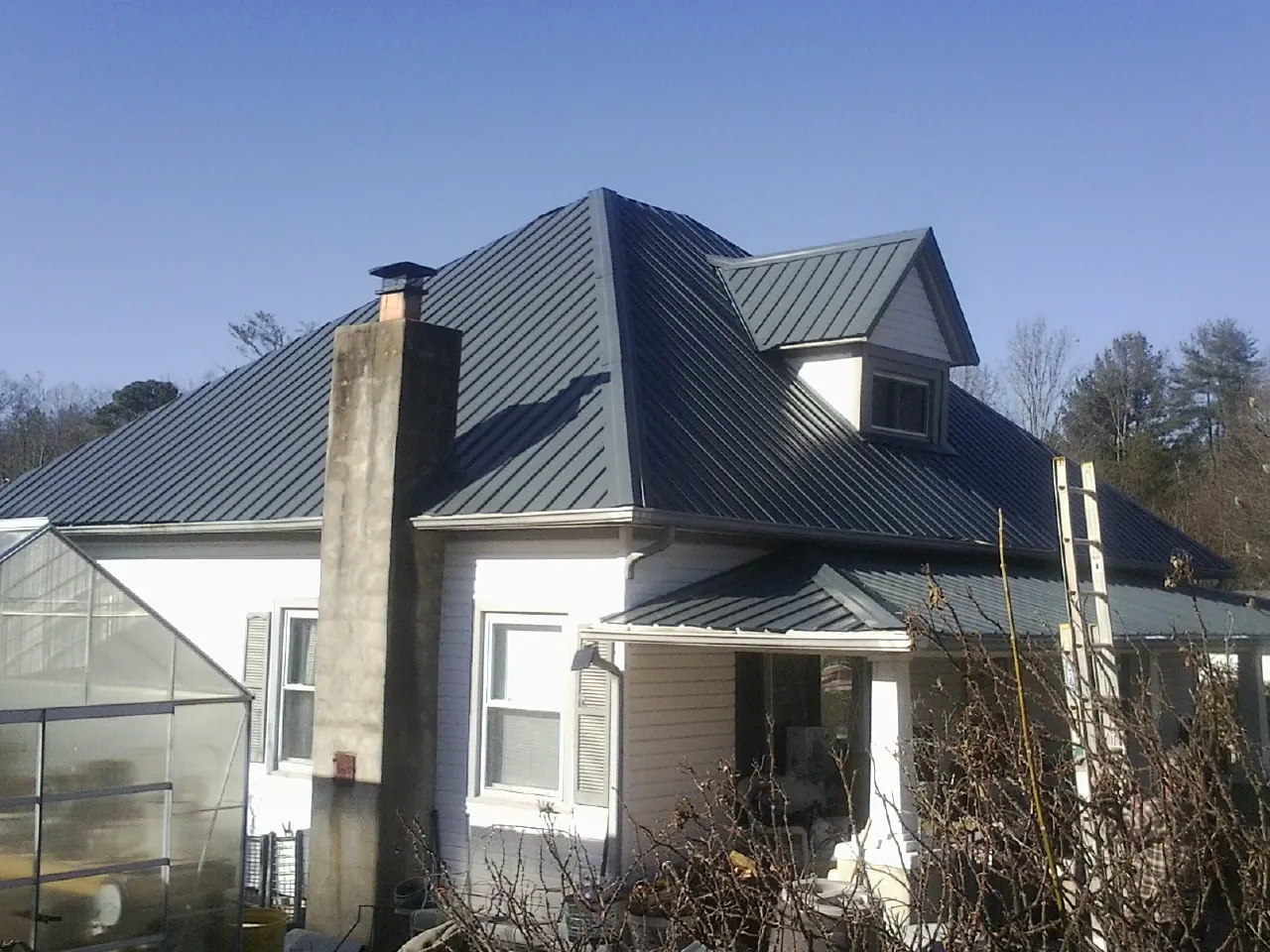 Dark blue standing seam metal roof on a white farmhouse with dormer — Slate & Tile Roof Repair by Roofing Brothers in Jessup