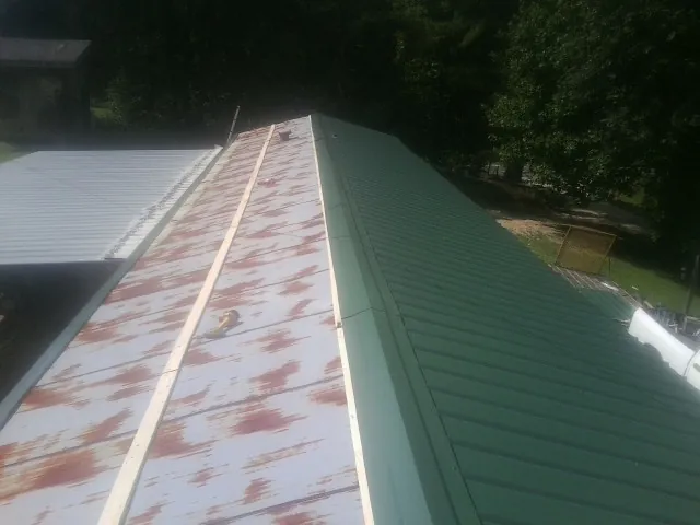 Old rusted panels beside newly installed green metal roofing — Wind Damage Roof Repair by Roofing Brothers in Jessup
