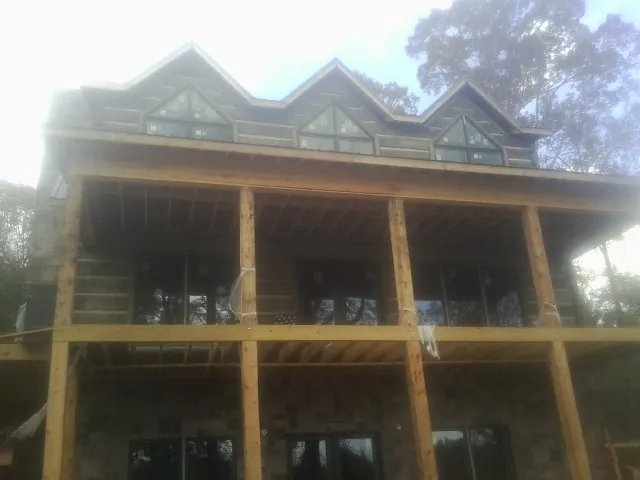Dormers and porch framing on a large log home under construction — Roof Coating work by our crew in Jessup