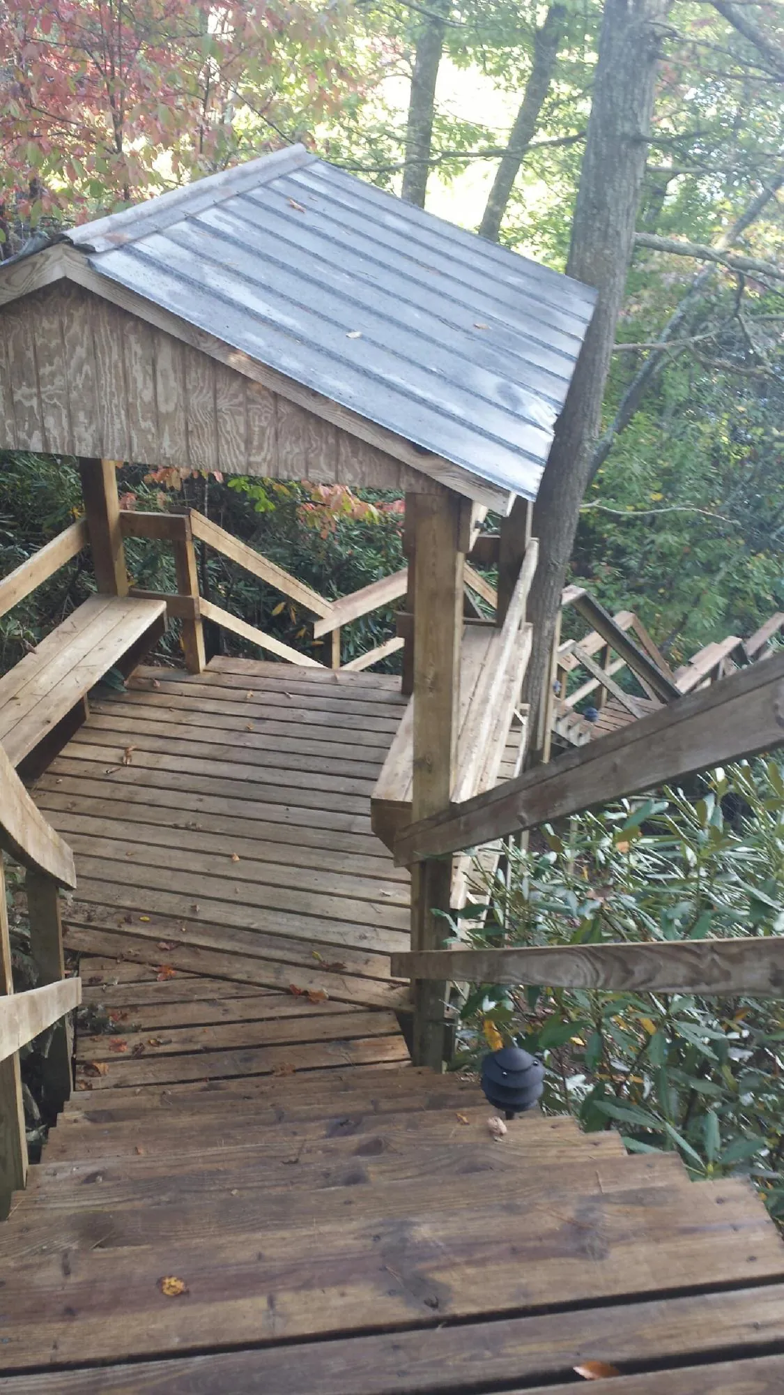 Metal roofed shelter over wooden steps on a wooded walkway — Skylight Repair & Installation work by our crew in Jessup