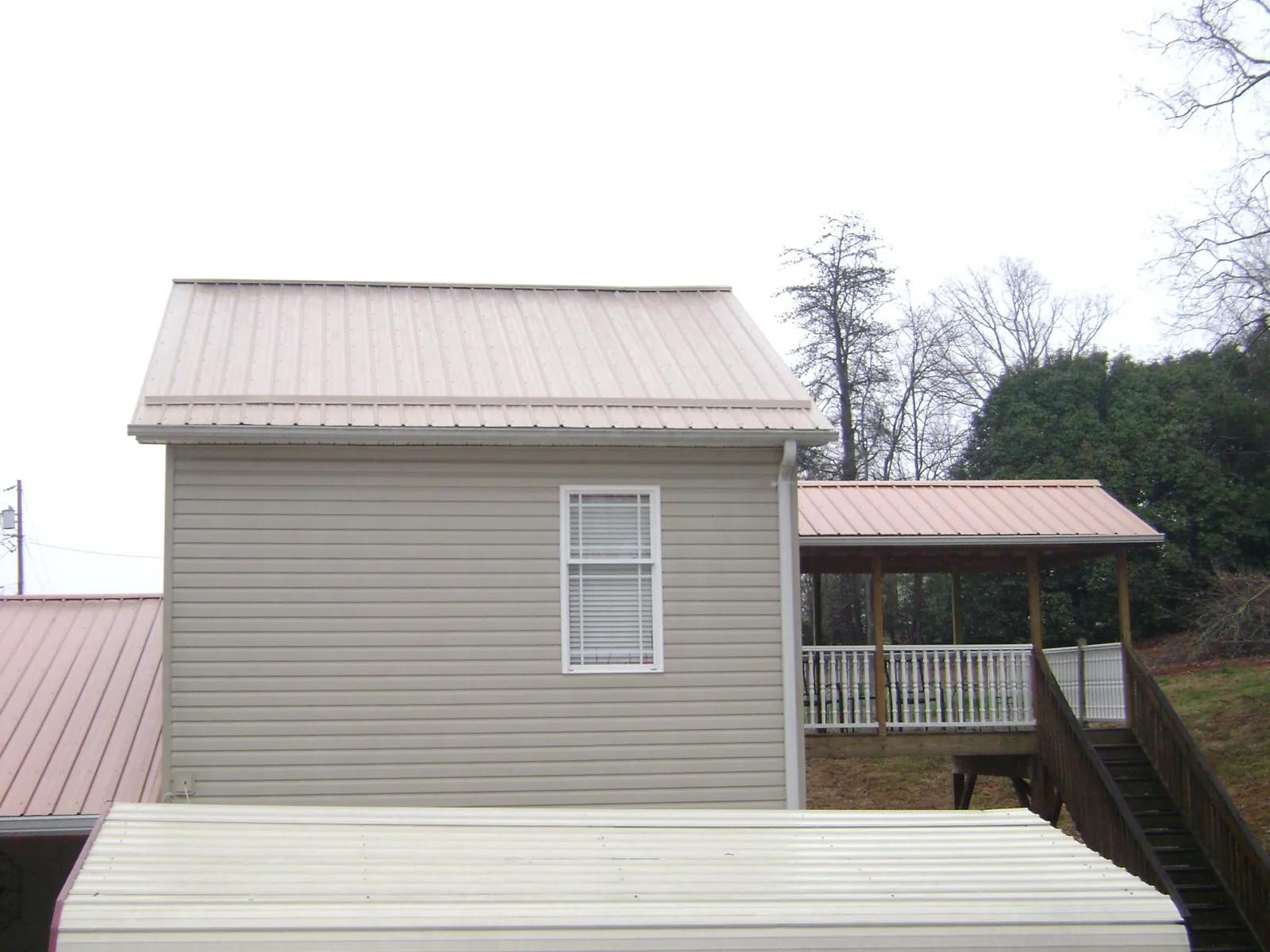 Tan metal roofs on a two story addition and attached porch, from a Roof Replacement job in Jessup